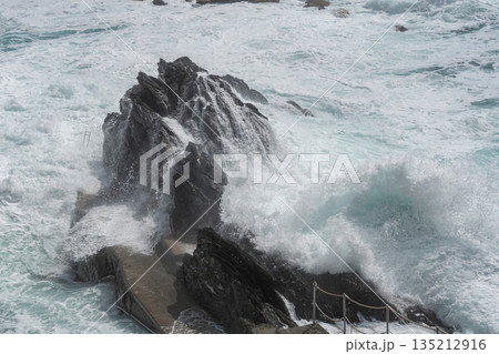 Strong sea waves crashing against dark coastal rocks. Dramatic motion, natural power and wild seascape atmosphere, ideal for nature and ocean strength concepts Strong sea waves crashing against dark coastal rocks. Dramatic motion, natural power and wild seascape atmosphere, ideal for nature and ocean strength concepts 135212916