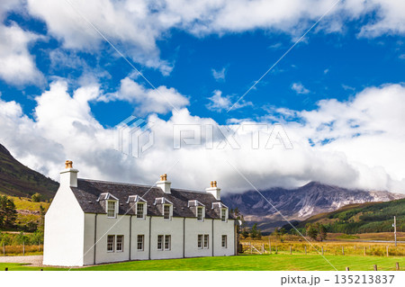 Traditional white cottage in Scottish Highlands mountain landscape 135213837