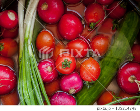 Bunch of fresh vegetables rinsed in the bowl with water in the sink, close up of veggies in the bowl covered with water drops. 135214248