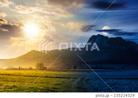 springtime in countryside. day and night time change concept. beautiful scenery with green grassy field with sun and moon. rocky cliff above the forested hill. duality and transition template springtime in countryside. day and night time change concept. beautiful scenery with green grassy field with sun and moon. rocky cliff above the forested hill. duality and transition template 135214329