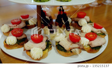 Small elegant sandwiches with various ingredients are beautifully arranged on a two tier serving platter, perfect for a sophisticated event or celebration 135215137