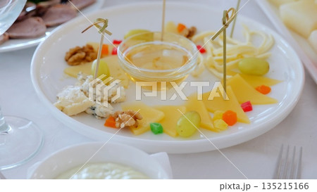 Gourmet cheese plate displaying artisan varieties, honey, walnuts, grapes, candied fruitelegant appetizer showcasing rustic culinary presentation 135215166