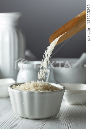 Raw organic rice is poured in white bowl. 135215269