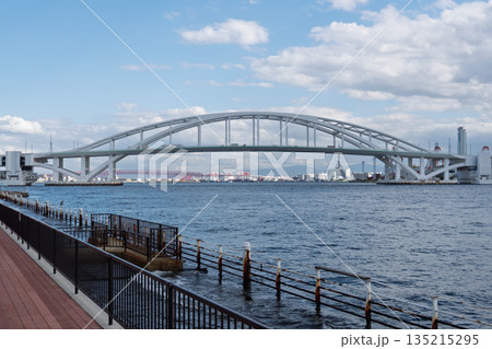 青空の下で大阪湾に架かる夢舞大橋の美しいアーチ形状と水辺の風景（世界初の浮体式旋回可動橋） 135215295