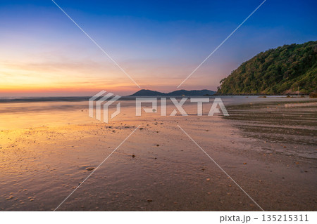 Beautiful tropical beach at sunset with golden light reflecting on the wet sand under a vibrant twilight sky Beautiful tropical beach at sunset with golden light reflecting on the wet sand under a vibrant twilight sky 135215311