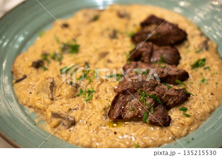 Risotto with sliced meat steak served on plate. It is a popular Italian rice dish. Risotto with sliced meat steak served on plate. It is a popular Italian rice dish. 135215530