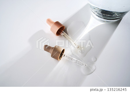Skincare droppers with cosmetic serum and water spills on white background Skincare droppers with cosmetic serum and water spills on white background 135216245