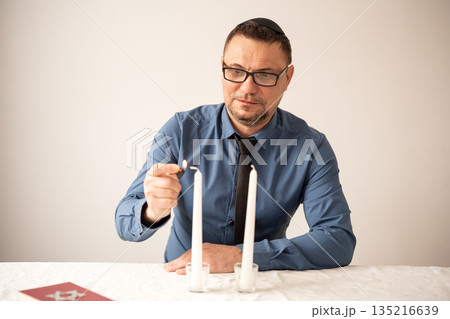 Jewish man lighting Shabbat candles. Shabbat Shalom. 135216639