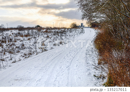 Snow covered rural road under winter sky 135217011