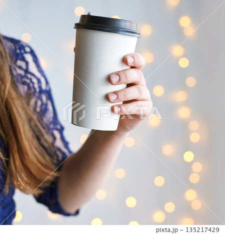 Caucasian female holding coffee cup against soft bokeh light background 135217429