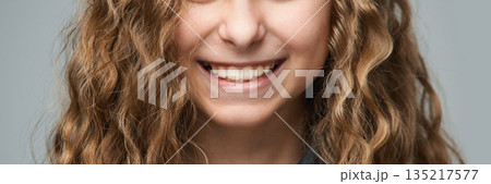 Smiling young caucasian female with curly brown hair and bright smile against Smiling young caucasian female with curly brown hair and bright smile against 135217577