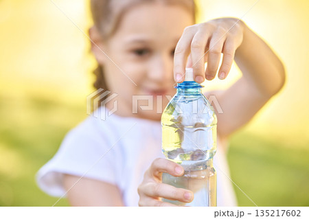 Hispanic female child opening water bottle in sunny outdoor setting with focus Hispanic female child opening water bottle in sunny outdoor setting with focus 135217602