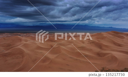 Sand dunes with storm clouds at sunset in desert 135217730