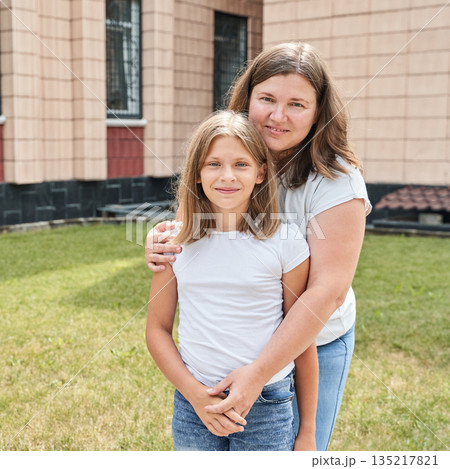 Caucasian adult female and young female smiling outdoors in casual attire Caucasian adult female and young female smiling outdoors in casual attire 135217821