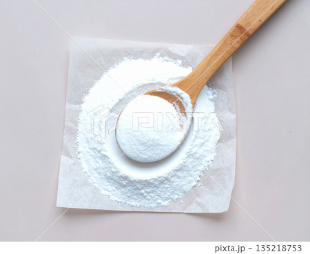 Cleaning concept. Pile of powdered detergent with a wooden spoon on kraft paper on a white background. 135218753