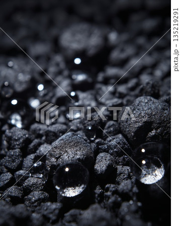 Water droplets resting on dark gravel surface, showcasing natural filtration concept and texture 135219291