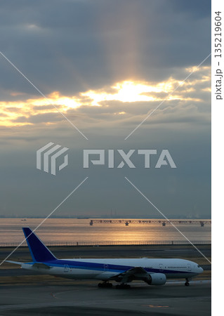 早朝の空港｜離陸前の旅客機_縦 135219604