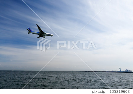 海上を低空飛行で着陸する旅客機 135219608