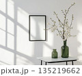 Minimal interior with wall mirror and vase of blossom branches 135219662