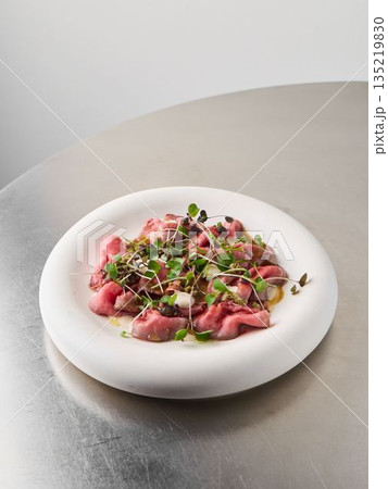 Thinly sliced tuna garnished with microgreens and lemon zest Thinly sliced tuna garnished with microgreens and lemon zest 135219830