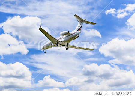 Private business plane flying under blue sky with white cloud 135220124