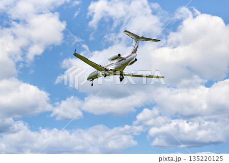 Private business plane flying under blue sky with white cloud 135220125
