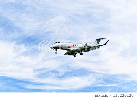 Private business plane flying under blue sky with white cloud 135220126