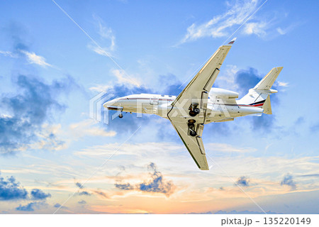 Private business jet flying under the sunset sky Private business jet flying under the sunset sky 135220149