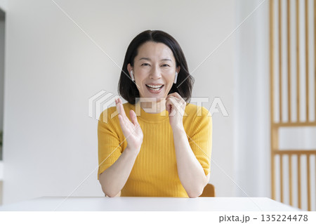 カメラ目線で話すイヤホンをつけた50代の女性 カメラ目線で話すイヤホンをつけた50代の女性 135224478