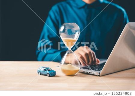 Car loan payment deadline approaching, businessperson managing finances on laptop, miniature car with flowing sand hourglass signifies buying cost and saving money over time Car loan payment deadline approaching, businessperson managing finances on laptop, miniature car with flowing sand hourglass signifies buying cost and saving money over time 135224908