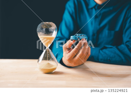 Individual holds car, hourglass shows time passing, symbolizing finance, loan, and saving money, crucial for understanding car cost, insurance, and depreciation for business 135224921