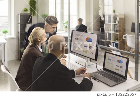 Business team analyzing data charts on screens during office strategy meeting Business team analyzing data charts on screens during office strategy meeting 135225057