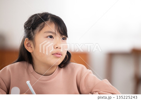 タブレットで勉強しながら微笑む小学生の女の子 タブレットで勉強しながら微笑む小学生の女の子 135225243