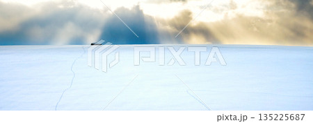 冬の北海道美瑛町の雪原の向こうに落ちる太陽と雲からの光芒 135225687