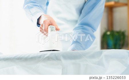 ワイシャツのアイロン掛けをする女性の手元 135226033