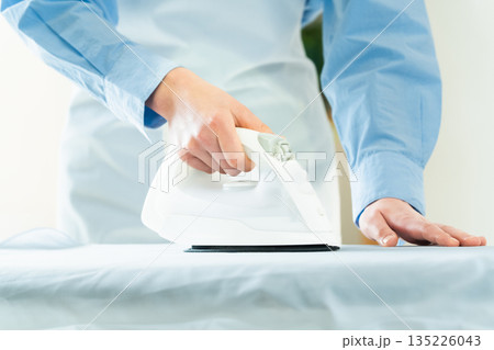 ワイシャツのアイロン掛けをする女性の手元 135226043