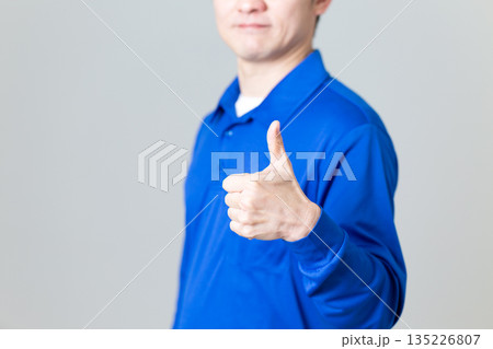 ガッツポーズをする物流・運送業の青い作業着を着たミドル男性 135226807