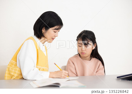 女子児童に勉強を教える学童指導員の女性 135226842