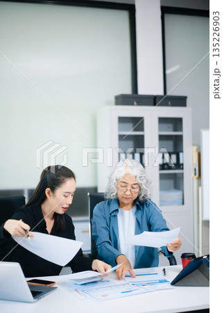 Asian senior and middle aged businesswomen working together in office, using smartphone and tablet 135226903