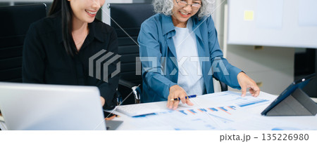 Asian senior and middle aged businesswomen working together in office, using smartphone and tablet 135226980