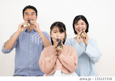恵方巻きを丸かぶりする3人家族 135227320