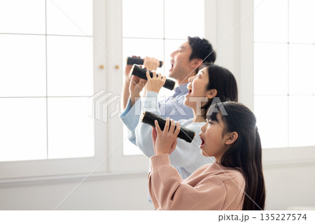 明るいリビングで恵方巻きを丸かぶりする3人家族 135227574