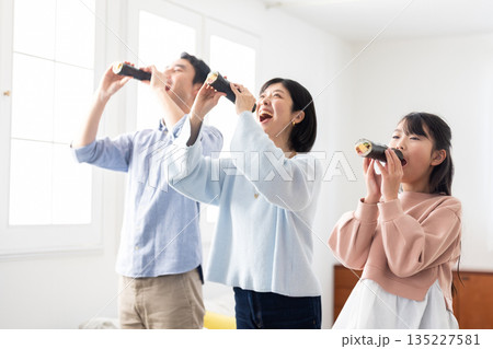 明るいリビングで恵方巻きを丸かぶりする3人家族 明るいリビングで恵方巻きを丸かぶりする3人家族 135227581