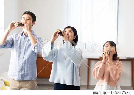 明るいリビングで恵方巻きを丸かぶりする3人家族 明るいリビングで恵方巻きを丸かぶりする3人家族 135227583