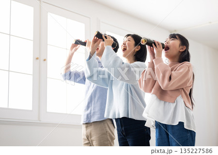 明るいリビングで恵方巻きを丸かぶりする3人家族 135227586