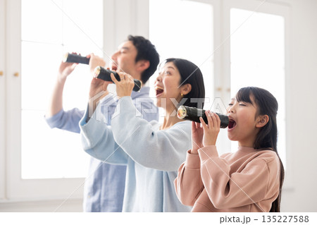 明るいリビングで恵方巻きを丸かぶりする3人家族 明るいリビングで恵方巻きを丸かぶりする3人家族 135227588