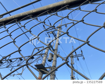 金網フェンス越しに見上げる電柱と青空 金網フェンス越しに見上げる電柱と青空 135227589