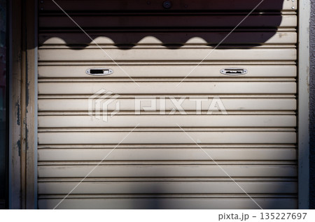 A closeup shot of automatic metal roller door used in factory, storage, garage, and industrial warehouse. The corrugated and foldable metal sheet offer space saving and provide urban and rustic feel A closeup shot of automatic metal roller door used in factory, storage, garage, and industrial warehouse. The corrugated and foldable metal sheet offer space saving and provide urban and rustic feel 135227697