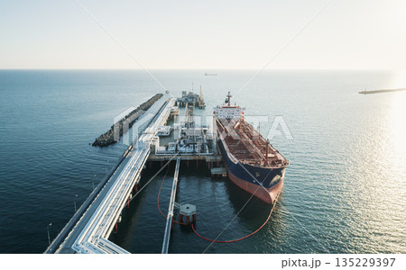 Aerial view of a large oil tanker docked at a pier in the port in process of loading. 135229397