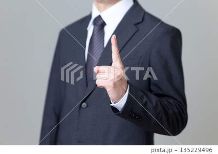人差し指を立てるスーツ姿のミドル男性ビジネスマン 135229496